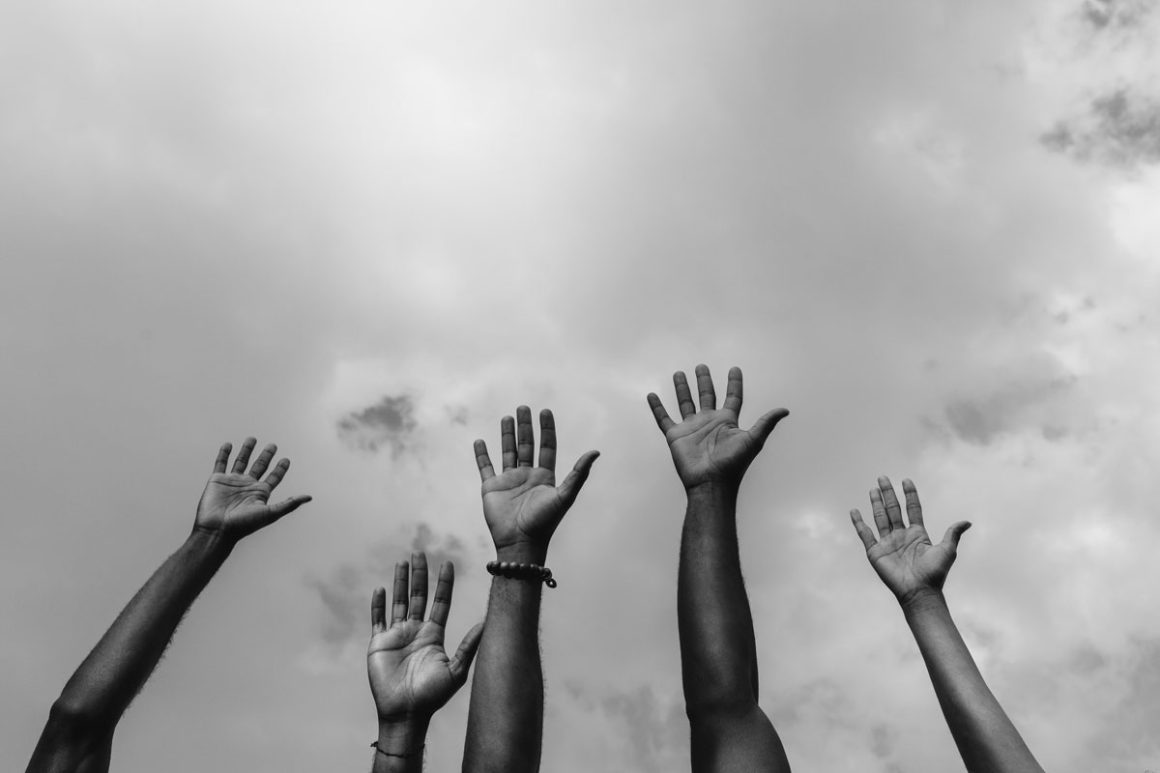 Cropped photo of five Africans raising arms white fighting for social rights.