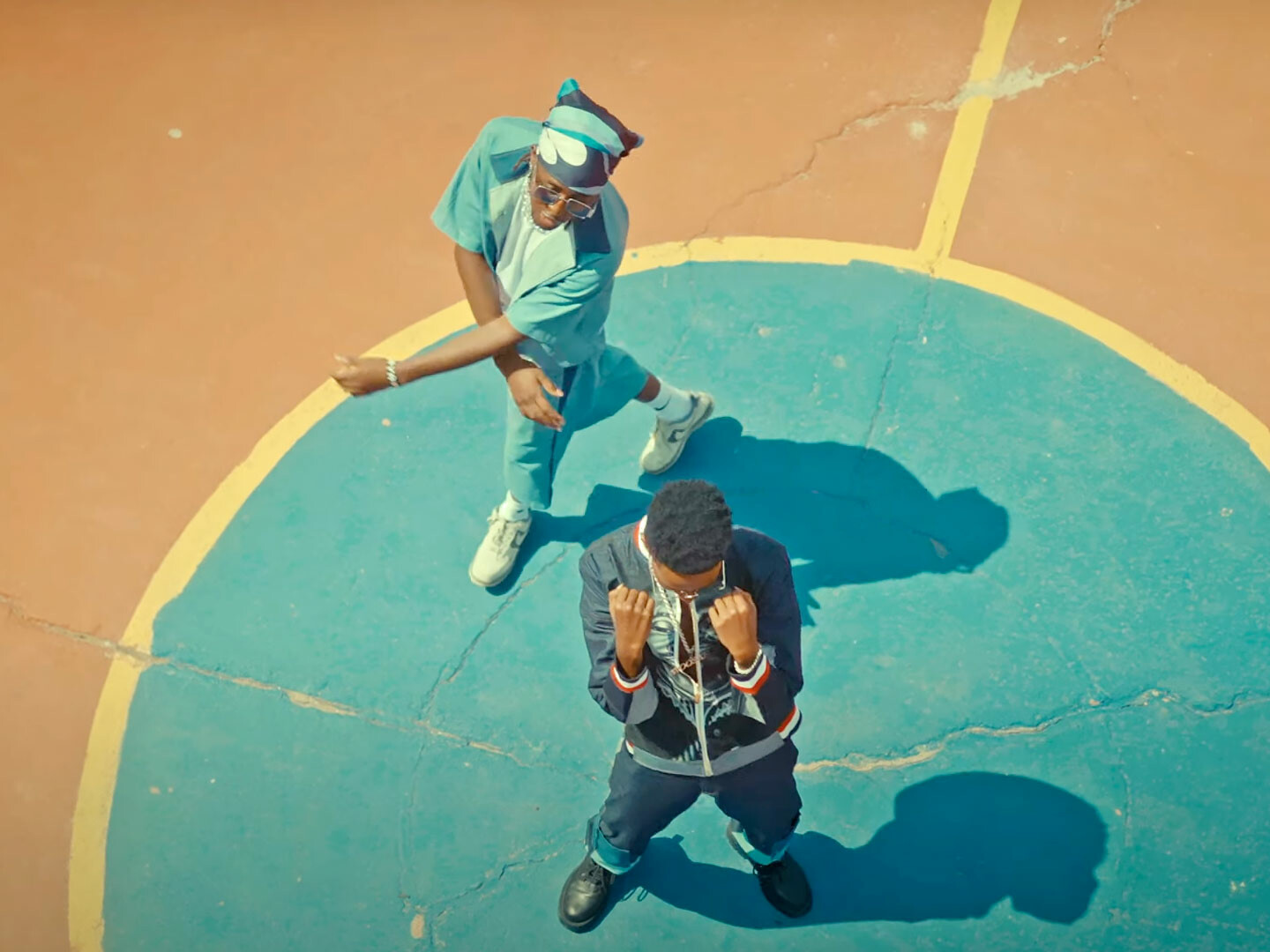 Bird's eye image of Kenyan artists Mr.Tee and Fidel Rayd standing on a basketball court during a performance of their song Turn Off