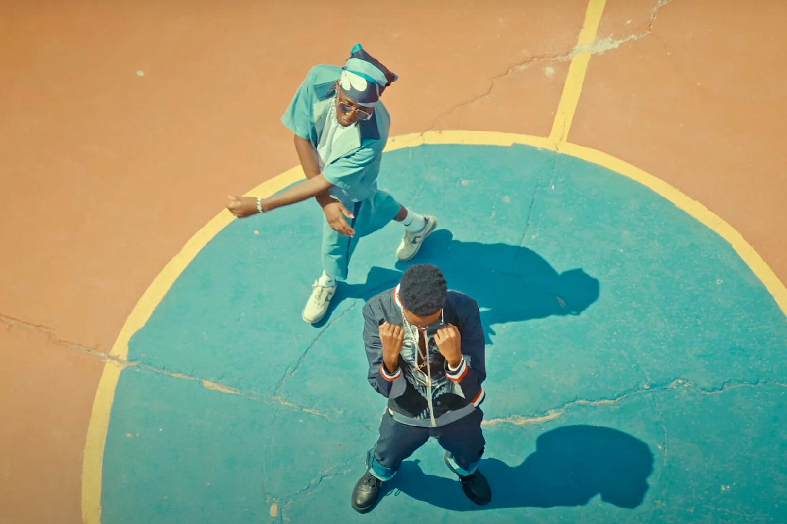 Bird's eye image of Kenyan artists Mr.Tee and Fidel Rayd standing on a basketball court during a performance of their song Turn Off