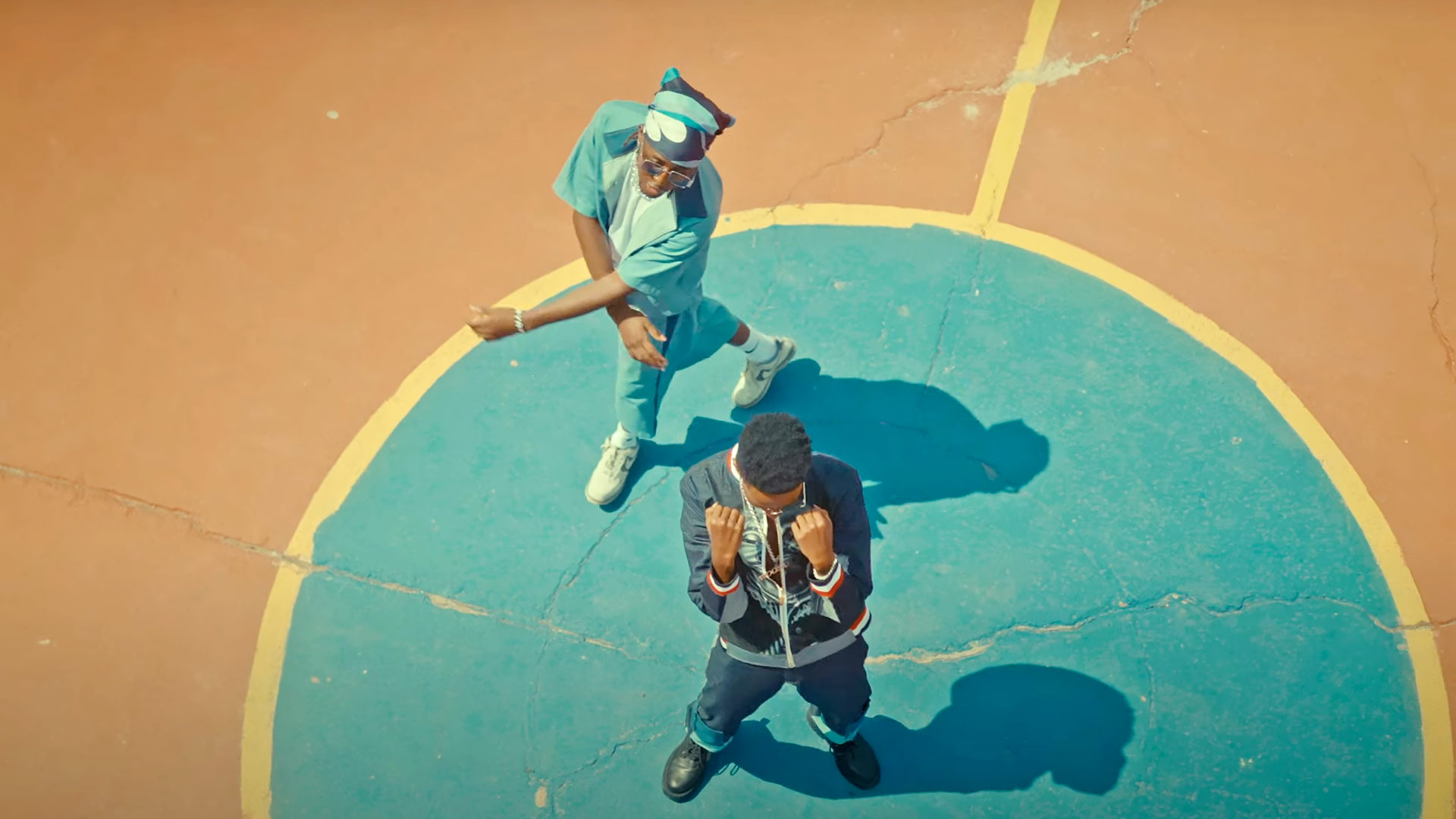 Bird's eye image of Kenyan artists Mr.Tee and Fidel Rayd standing on a basketball court during a performance of their song Turn Off